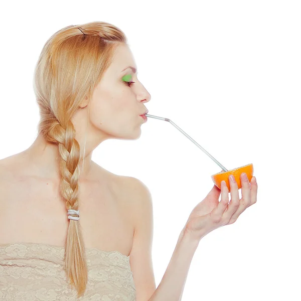 Mooie jonge vrouw drinken sap direct uit een oranje fruit — Stockfoto