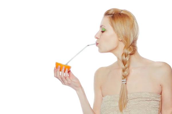 Mooie jonge vrouw drinken sap direct uit een oranje fruit — Stockfoto