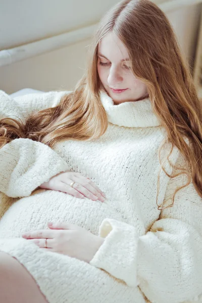 Raskaana oleva nainen istuu sohvalla — kuvapankkivalokuva