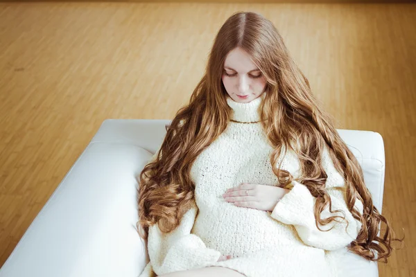 Gravid kvinna som sitter på soffan — Stockfoto