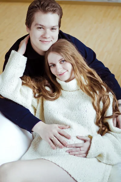 Young pregnant woman and man sitting on sofa — Stock Photo, Image