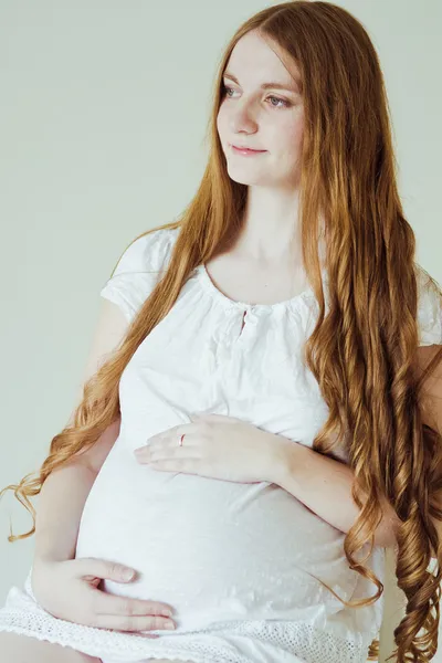 Gravid kvinde sidder på stol - Stock-foto