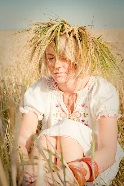 Schönes Mädchen in einem traditionellen slawischen Kranz auf einem Feld aus goldenem Weizen — Stockfoto