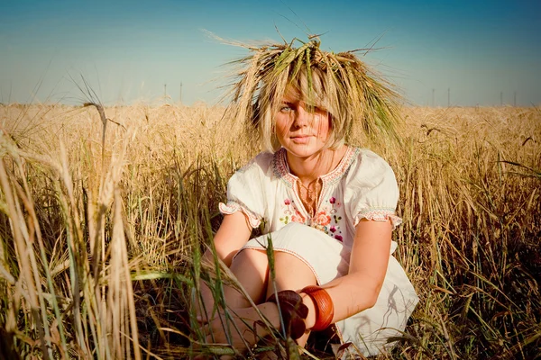 Όμορφο κορίτσι σε ένα παραδοσιακό σλαβική στεφάνι σε ένα πεδίο της χρυσό σιτάρι — Φωτογραφία Αρχείου