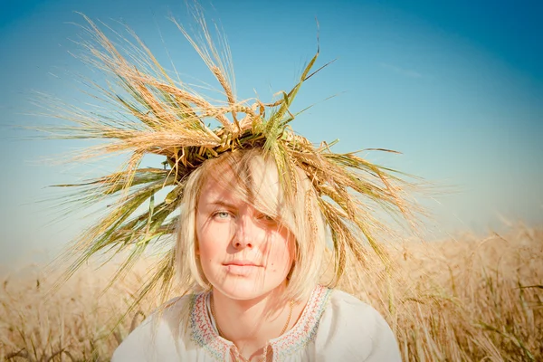 Bella ragazza in una tradizionale ghirlanda di slavi su un campo di grano dorato — Foto Stock