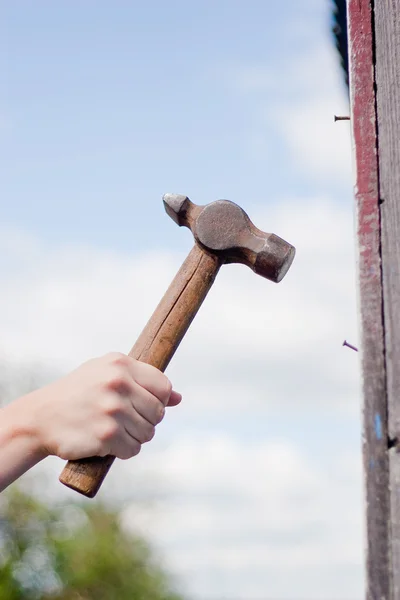 Hand with hammer on sky background — Stock Photo, Image