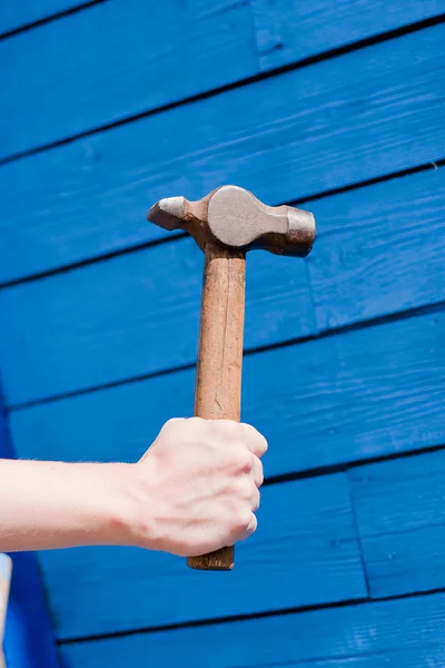 Hand with hammer on blue wooden background — Stock Photo, Image