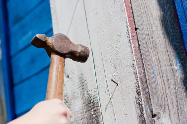 Hand with hammer on blue wooden background — Stock Photo, Image