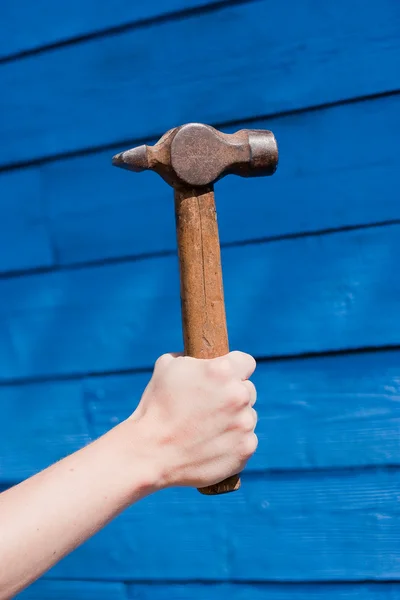 Hand with hammer on blue wooden background — Stock Photo, Image
