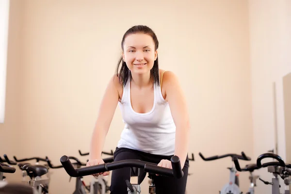 Giovane donna in sella a una cyclette di allenamento — Foto Stock