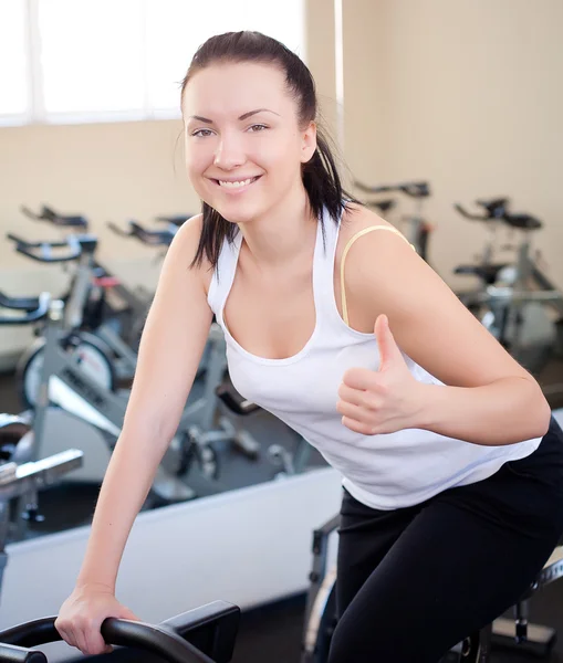 Mujer joven montando una bicicleta de ejercicios de entrenamiento — Foto de Stock