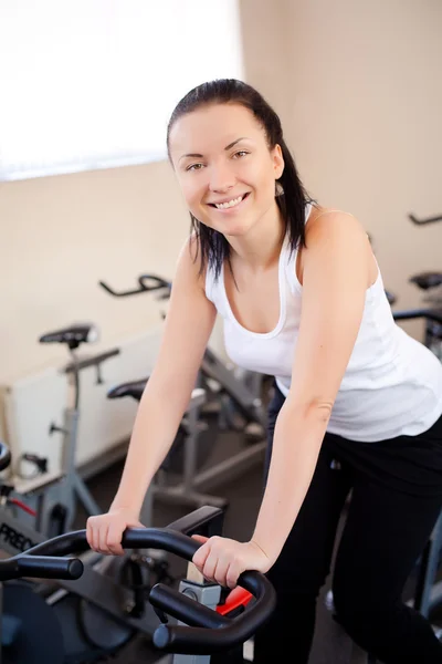 Mujer joven montando una bicicleta de ejercicios de entrenamiento — Foto de Stock