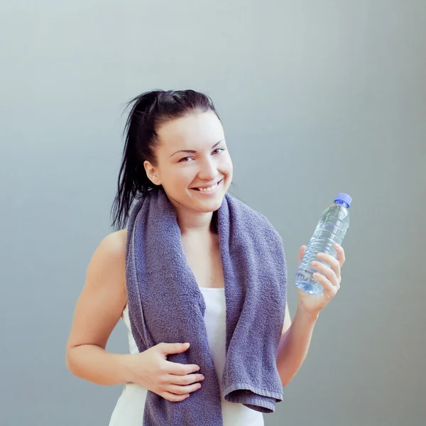 Jonge vrouw drinken van water, op fitnessclub of sportschool — Stockfoto