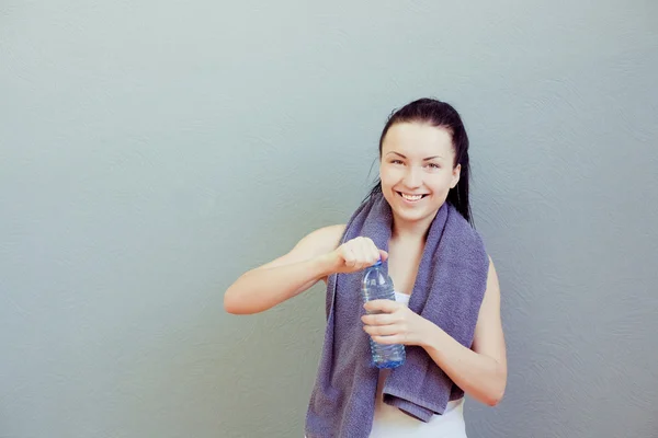 Молода жінка п'є воду, у фітнес-клубі або спортзалі — стокове фото