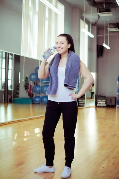Junge Frau trinkt Wasser, im Fitnessclub oder Fitnessstudio — Stockfoto