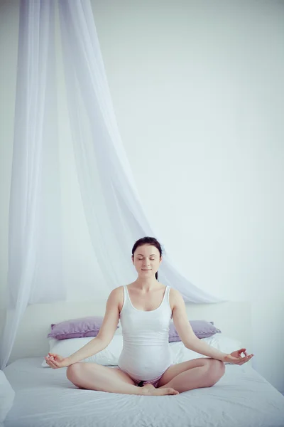 Jeune femme enceinte pratiquant le yoga dans la chambre — Photo