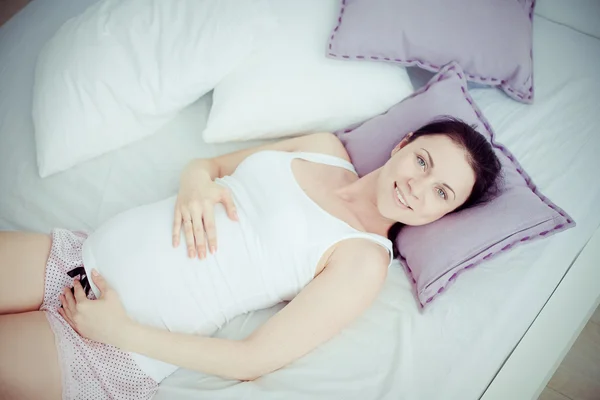 Giovane donna incinta in camera da letto — Foto Stock