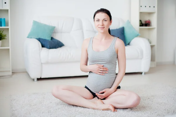 Genç hamile kadın içeride yoga yapıyor. — Stok fotoğraf