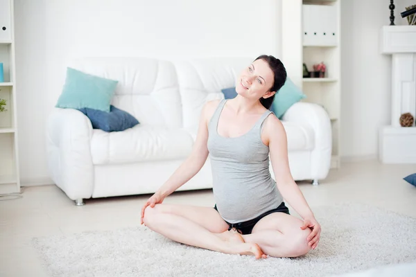 Genç hamile kadın içeride yoga yapıyor. — Stok fotoğraf