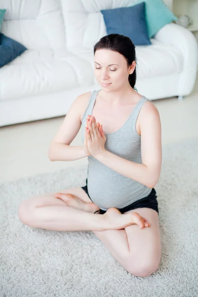 Genç hamile kadın içeride yoga yapıyor. — Stok fotoğraf