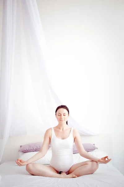 Joven embarazada practicando yoga en el dormitorio — Foto de Stock