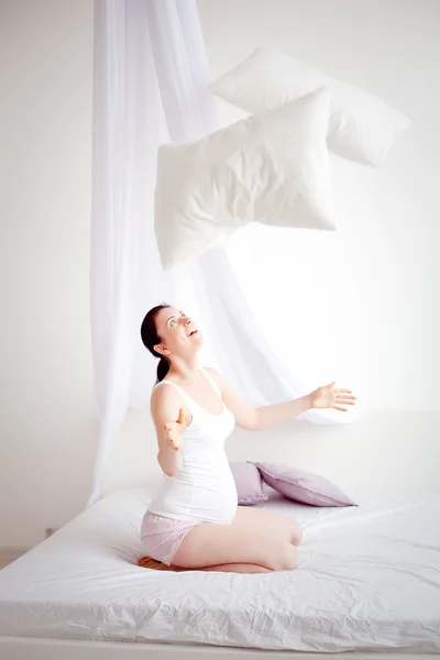 Junge schwangere Frau wirft Kissen ins Schlafzimmer — Stockfoto