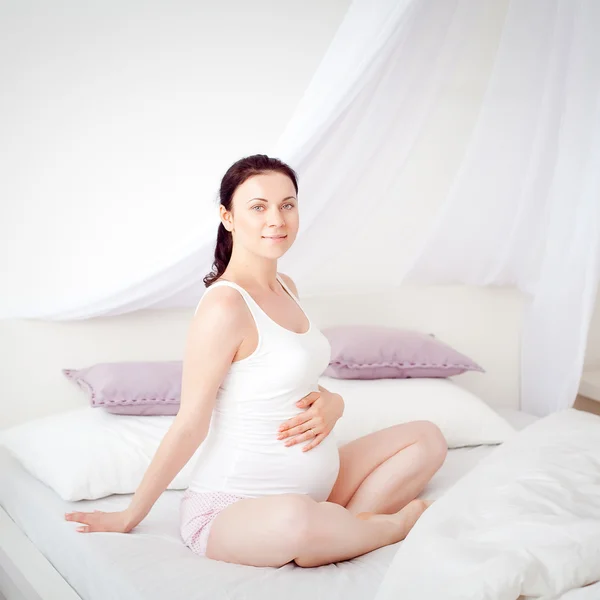 Junge schwangere Frau im Schlafzimmer lizenzfreie Stockfotos