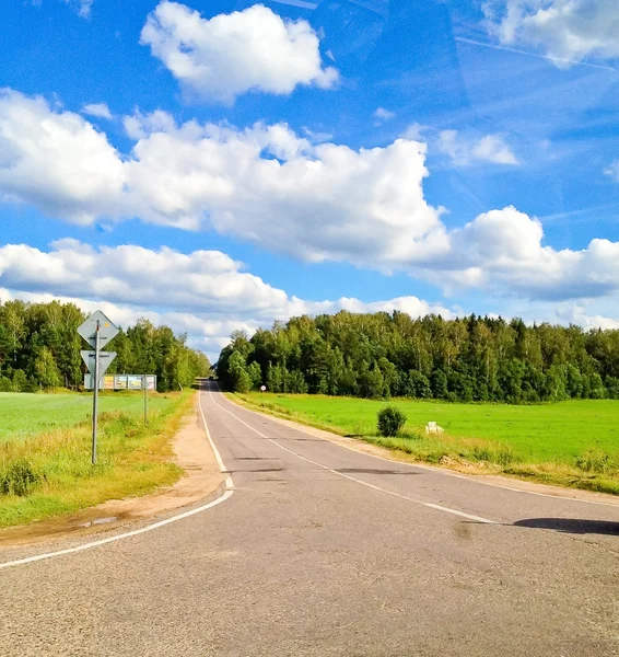 Yeşil çimen, yol ve bulutlar manzara — Stok fotoğraf