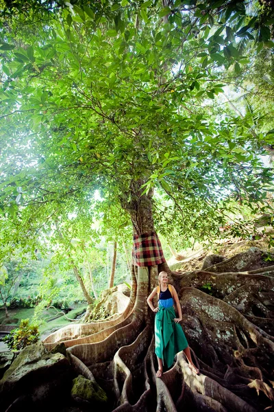 Ağaç kökleri üzerinde duran genç kadın — Stok fotoğraf