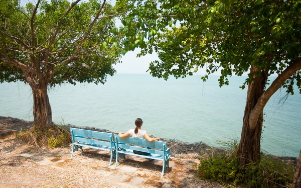 Jonge vrouw zittend op de Bank met uitzicht op zee — Stockfoto