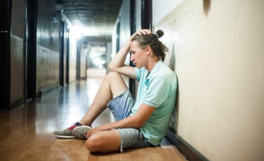 genç adam yerde oturup endişeli