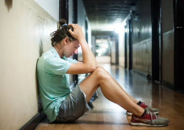 Jonge man bezorgd zittend op de vloer — Stockfoto