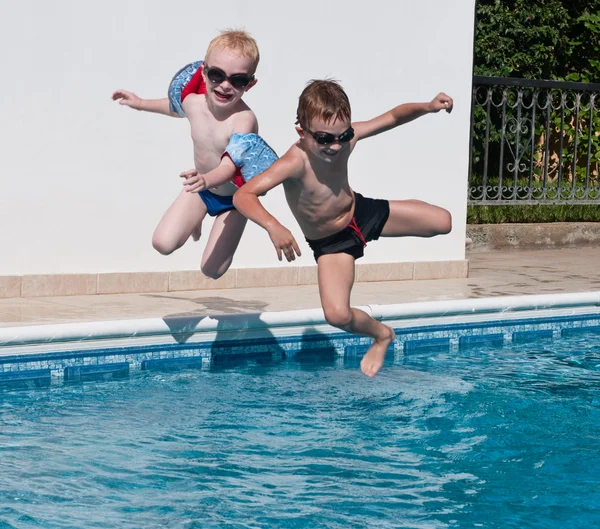 Two boys jumping into swimming pool — Stock Photo, Image