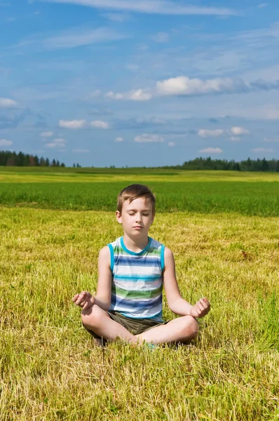 Jongen mediteren op het groene veld — Stockfoto