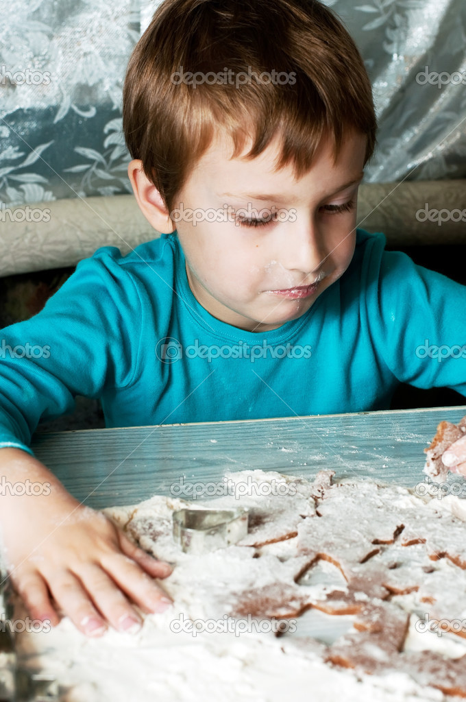 young boy making and tasting christmas cookies