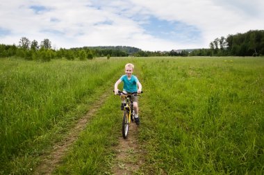 nice boy cycling in the field clipart