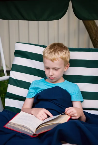 6 - årig pojke läser bok utomhus — Stockfoto