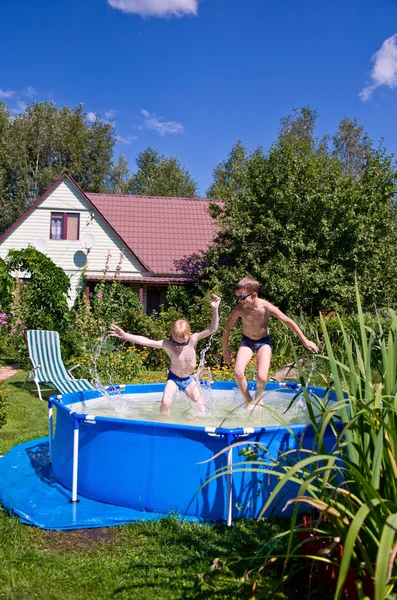 Два хлопчики стрибають і плескають у басейні Стокове Фото