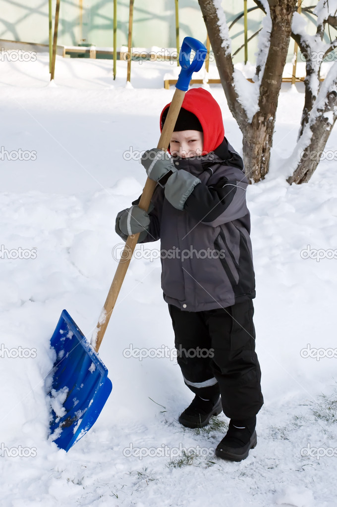 young boy with shovel helping cleaning the snow