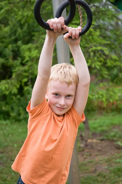 Ung dreng udøver på gym ringe - Stock-foto