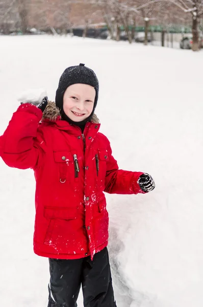 Leende pojke kastar snöboll — Stockfoto