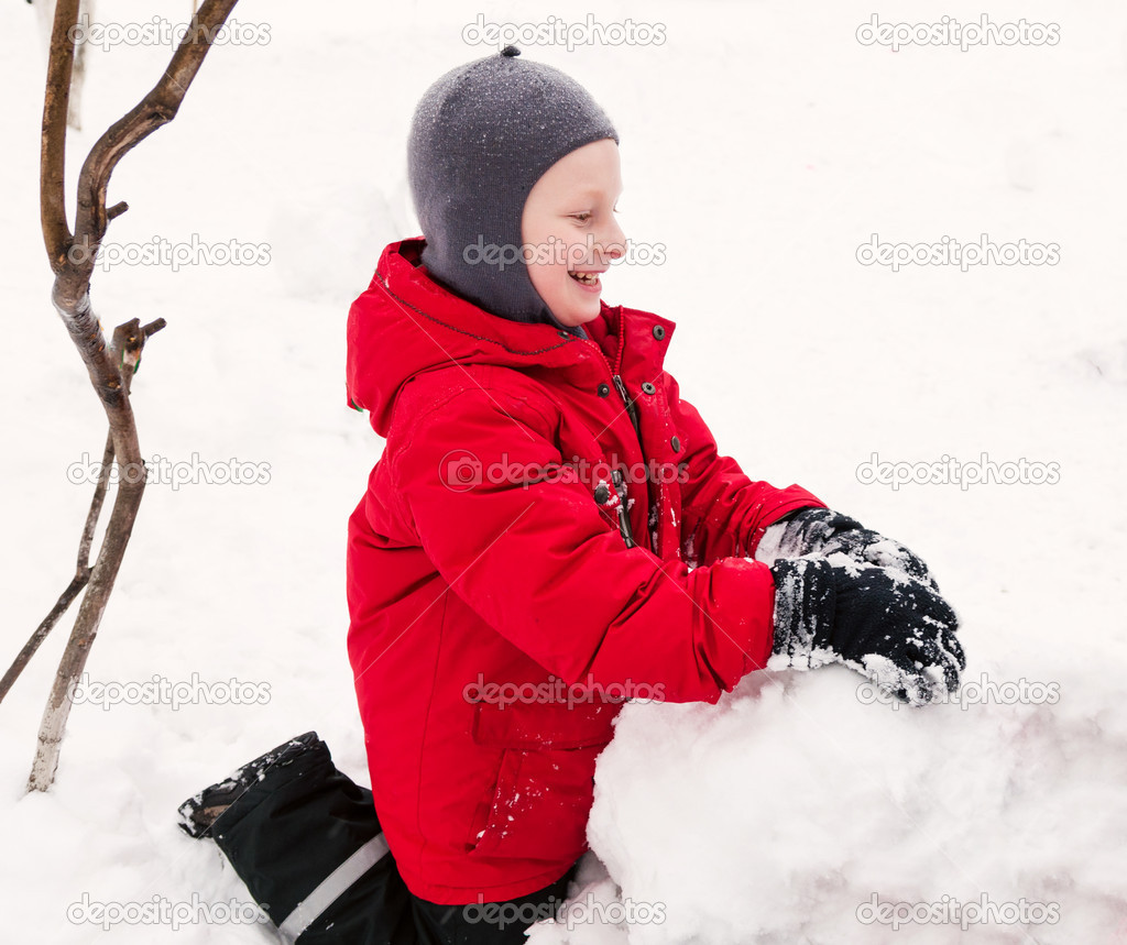 Smiling boy making snowman.