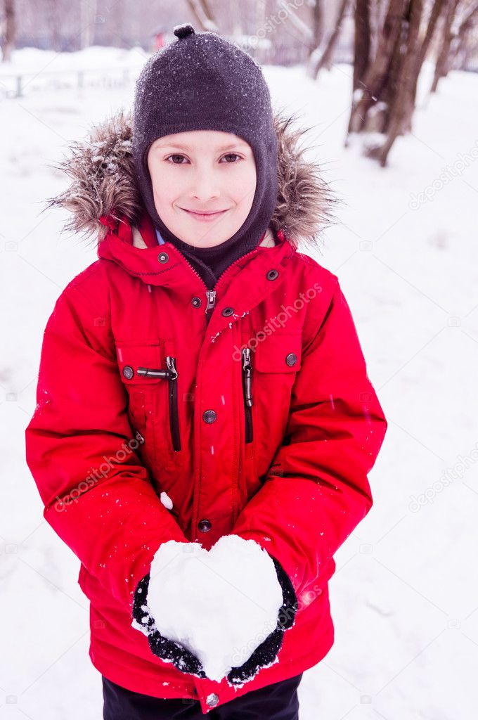 Smiling boy holding snow heart