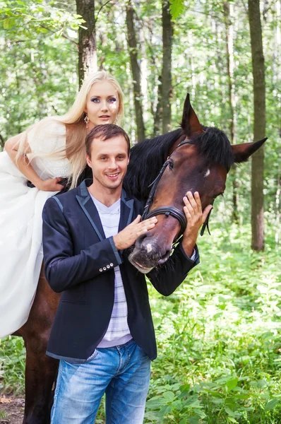 Couple nouvellement marié debout à côté d'un cheval — Photo