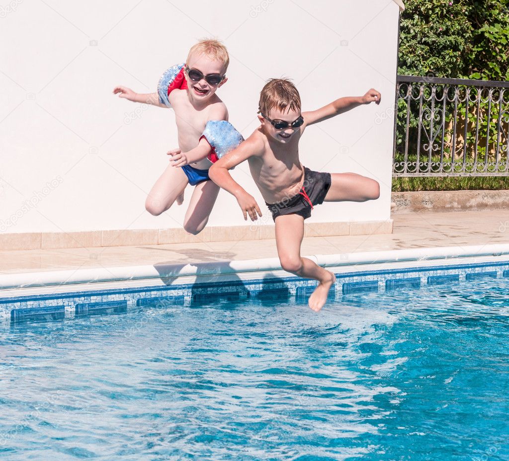 Two boys jumping into swimming pool