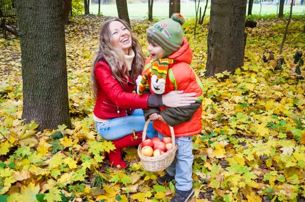 Familia feliz sonriendo y sosteniendo hojas de otoño — Foto de Stock