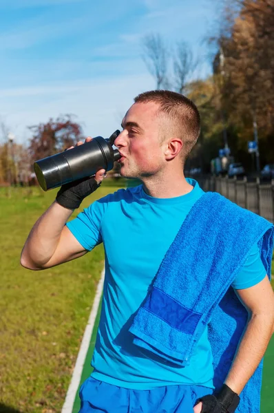 Jogger drinking water after workout — Stock Photo, Image