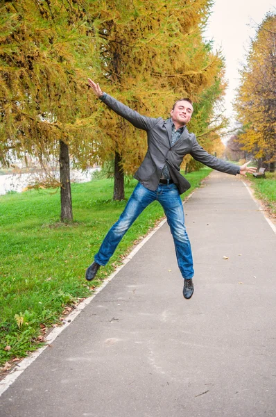 Young man jumping in autumn park — Stock Photo, Image