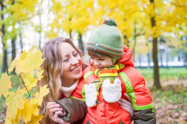 Happy family smiling and holding autumn leaves — Stock Photo, Image