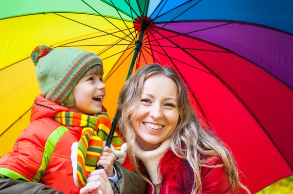 Famiglia felice con ombrellone colorato nel parco autunnale — Foto Stock